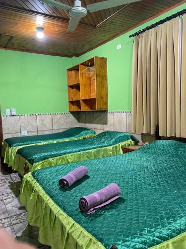 two beds with green sheets and purple pillows on them at Residencial Arcoiris in Puerto Iguazú
