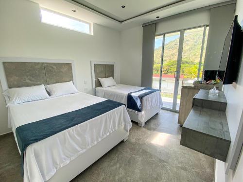 a bedroom with two beds and a large window at Hotel Campestre La María Toro Valle in Toro