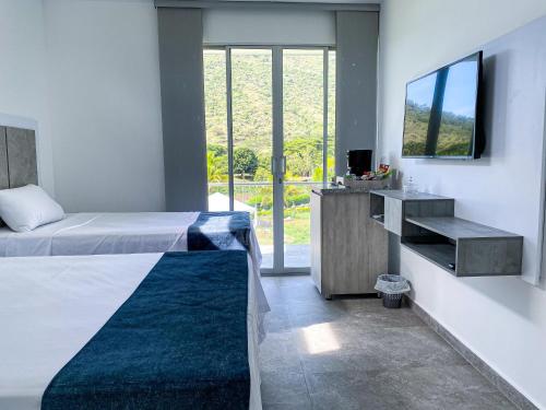 a bedroom with a bed and a tv on a wall at Hotel Campestre La María Toro Valle in Toro