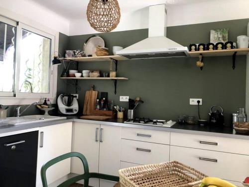 uma cozinha com armários brancos e uma parede verde em Maison au coeur de la Provence em Jonquerettes