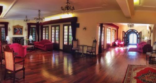 una gran sala de estar con muebles de color rojo y suelo de madera. en Hotel Aranjuez Cochabamba, en Cochabamba