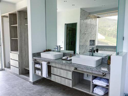 a bathroom with two sinks and a large mirror at Hotel Campestre La María Toro Valle in Toro