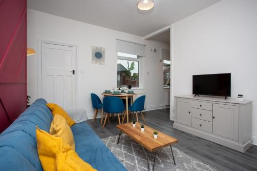 a living room with a blue couch and a table at The Ferndale - Spacious 3 Bed Apartment in Pallion