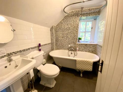 een badkamer met een toilet, een bad en een wastafel bij Quarry House in Presteigne