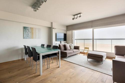 een woonkamer met een tafel en stoelen en een bank bij Seafront apartment 2 bed Duinbergen in Knokke-Heist
