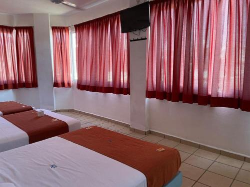 a hotel room with two beds and red curtains at Hotel Albatros in Pe&ntilde;ita de Jaltemba
