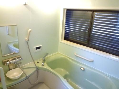 a bathroom with a tub and a toilet and a sink at GuestHouse AZMO - Vacation STAY 35375v in Matsue