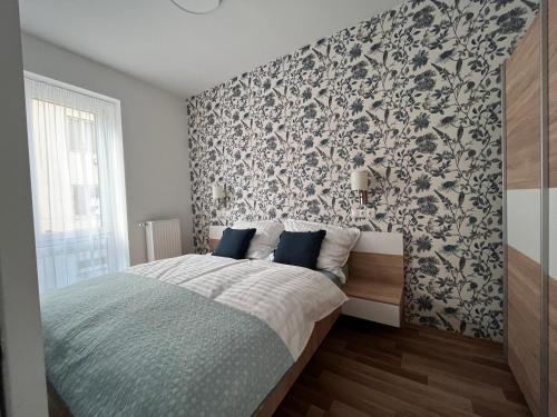 a bedroom with a bed with a black and white wallpaper at One Step Apartman - City Center with Self Check-In in Szombathely