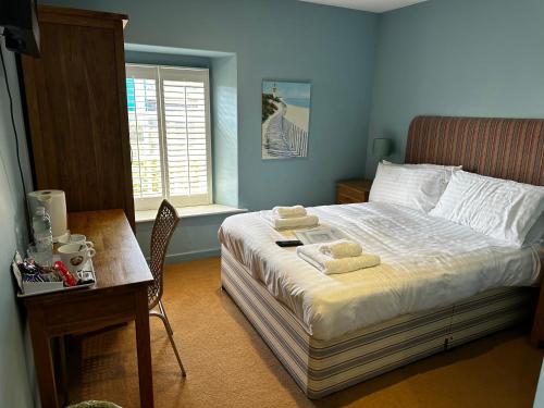 a bedroom with a bed and a desk with towels on it at Castle Hotel in Aberaeron