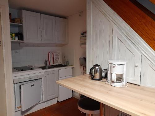 une cuisine avec des placards blancs et une cafetière sur un comptoir dans l'établissement Maison saisonnière de Mer, à Plage-des-Demoiselles