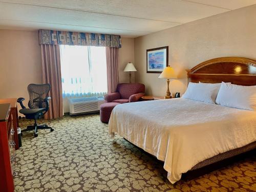 a hotel room with a bed and a chair and a window at ACP Hotel Westchase in Houston