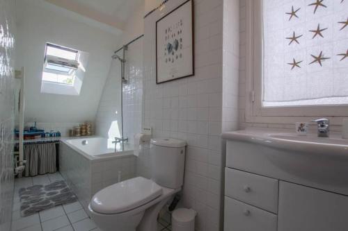 une salle de bain blanche avec des toilettes et un lavabo dans l'établissement CARNAC-Plage 12 personnes à 2mn à pied de la plage, à Carnac