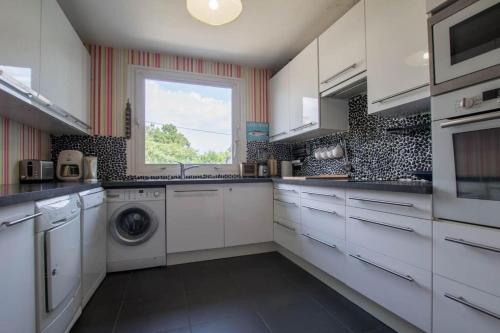 une cuisine blanche avec un lave-linge et une fenêtre dans l'établissement CARNAC-Plage 12 personnes à 2mn à pied de la plage, à Carnac