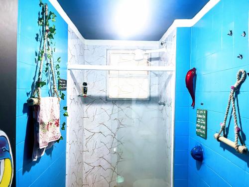 a bathroom with a shower with blue walls at Toca da Mona Roots Hostel in Vitória