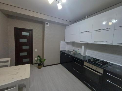 a kitchen with white cabinets and a black counter top at Apartament in Chişinău