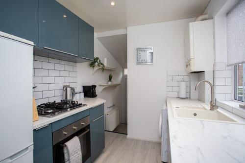 een keuken met blauwe kasten en een fornuis met oven bij The Brighton in Gateshead