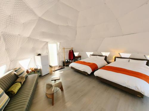 a bedroom with two beds and a couch in it at 奏の森リゾート　フォレストグランピング in Ito