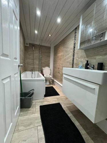 a bathroom with a tub and a toilet and a sink at Your Home-Big offers for Groups! in Leeds