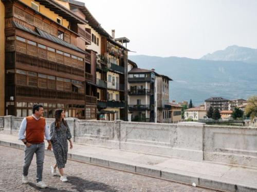 un hombre y una mujer caminando por una calle de la ciudad en La Casa dei Turchi, en Rovereto