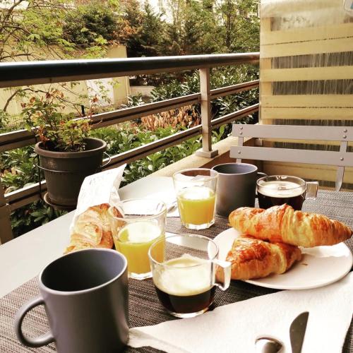 - une table avec des croissants, du café et des verres de jus d'orange dans l'établissement Part-Dieu : splendide 2 pièces calme sur verdure, à Lyon