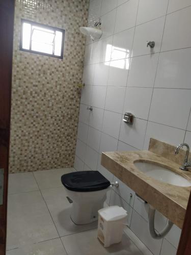 a bathroom with a toilet and a sink and a window at Casa agradável e confortável, com piscina in Bonito