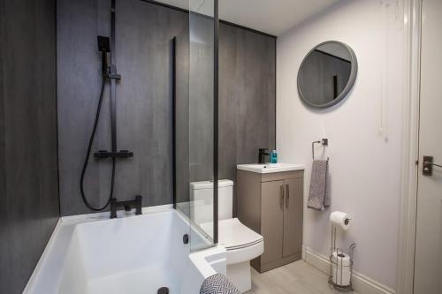 a bathroom with a tub and a toilet and a mirror at Stylish Cosy Two Bed Apartment - Coast Location in Whitley Bay