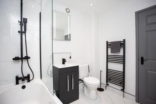 La salle de bains est pourvue d'un lavabo, de toilettes et d'une baignoire. dans l'établissement Modern Interior Spacious Four Bedroom Apartment, à Westoe