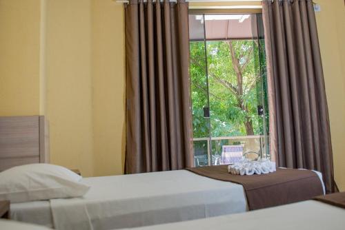 a bedroom with two beds and a large window at Hotel Iguaçu Centro in Foz do Iguaçu