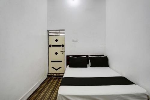 a small bedroom with a bed with white sheets and black pillows at OYO New River View in Jhājhar