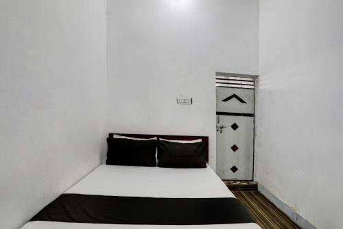 a bed in a room with a white wall at OYO New River View in Jhājhar