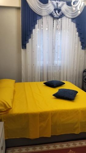 a yellow bed with two pillows in front of a window at La Casa di Sonia in Savona