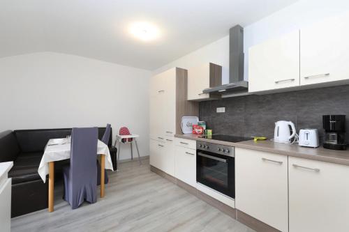 une cuisine avec des armoires blanches et une table à l'intérieur dans l'établissement Gîte spacieux propre proche Gérardmer, à Granges-sur-Vologne