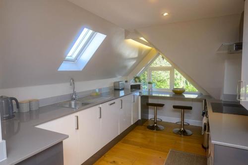 a kitchen with white cabinets and a skylight at Entire Apartment in Central Brockenhurst in Brockenhurst