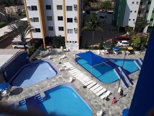 duas piscinas com guarda-sóis azuis ao lado de um edifício em Res Águas da Serra - 2 quartos em Caldas Novas