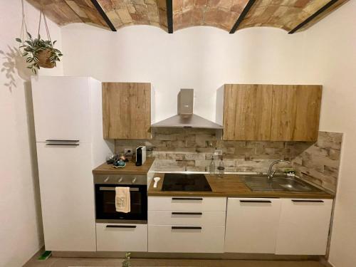 a kitchen with white cabinets and a sink and a stove at Casa Vacanze - La Torre - Appartamento in Marta