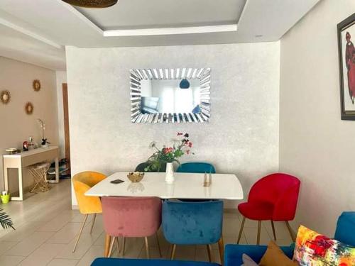 a dining room with a white table and colorful chairs at Résidence lina in Casablanca