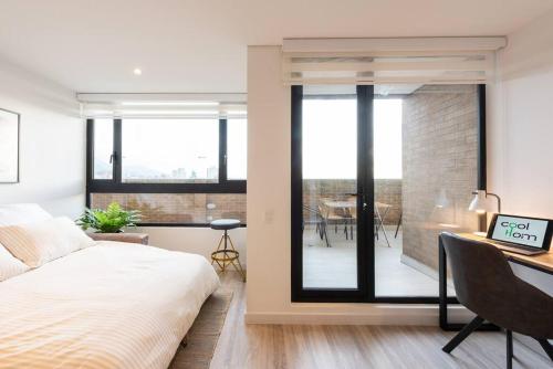 a bedroom with a bed and a desk and a balcony at 1305 Hermoso apartamento para estrenar in Bogotá