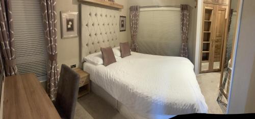 a bedroom with a white bed and a wooden table at Loubet Extra Large Lodge in Auchterarder