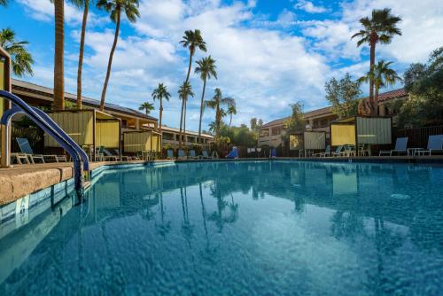 a large swimming pool with palm trees in the background at La Fuente Inn & Suites in Yuma