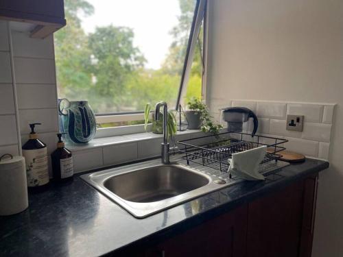 encimera de cocina con fregadero y ventana en Ealing Broadway bright flat, en Ealing