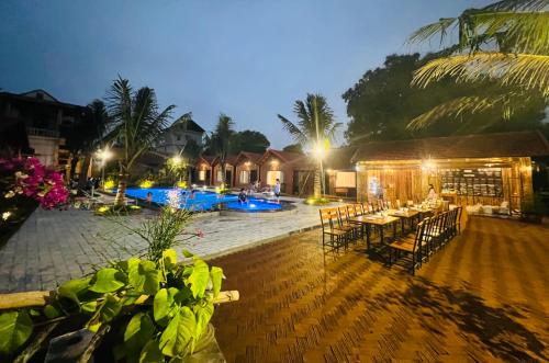 a patio with tables and chairs and a pool at night at Tam Coc Green Garden Bungalow in Ninh Binh