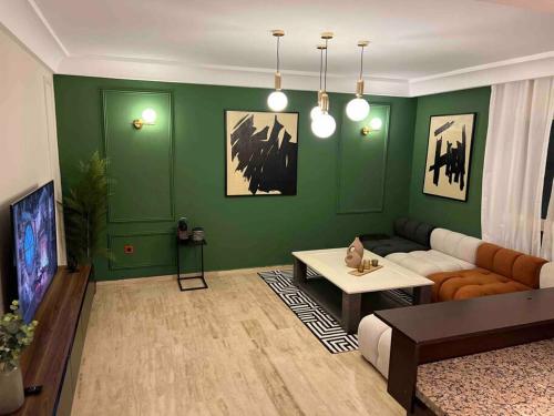 Luxurious 1bd room apartment in Agdal Rabat city في الرباط: غرفة معيشة مع جدران خضراء وأريكة
