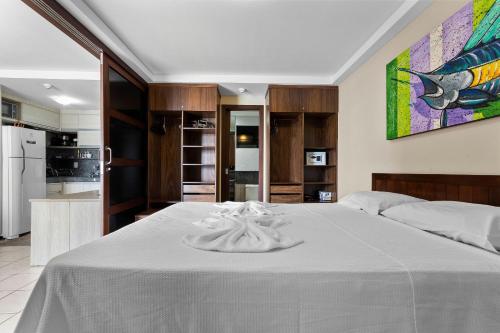 a bedroom with a white bed and a kitchen at Blue Marlim 2 quartos vista mar por Carpediem in Parnamirim