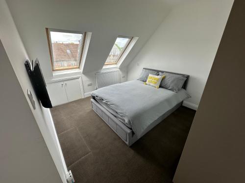 a small bedroom with a bed and two windows at Stunning Modern, Brand-New 1 Bed Flat Only 15 Mins To Central London in The Hyde