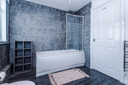 La salle de bains est pourvue d'une baignoire blanche et d'une douche. dans l'établissement Knutsford Road Moreton Wirral 3 bedroom 1 bathroom duplex apartment private parking by Rework Accommodation, à Moreton