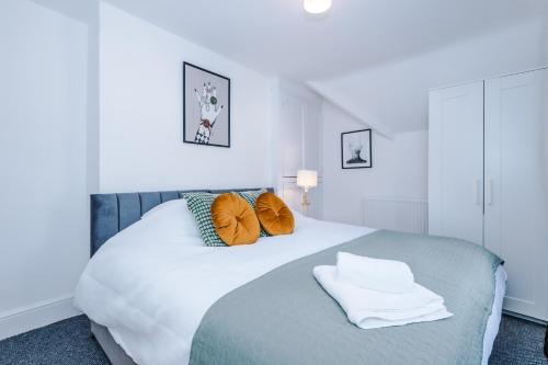 - une chambre avec un grand lit blanc et des oreillers orange dans l'établissement Knutsford Road Moreton Wirral 3 bedroom 1 bathroom duplex apartment private parking by Rework Accommodation, à Moreton