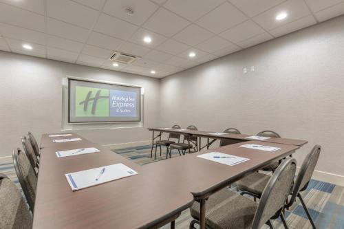 a conference room with tables and chairs and a screen at Holiday Inn Express & Suites Tulsa Midtown by IHG in Tulsa