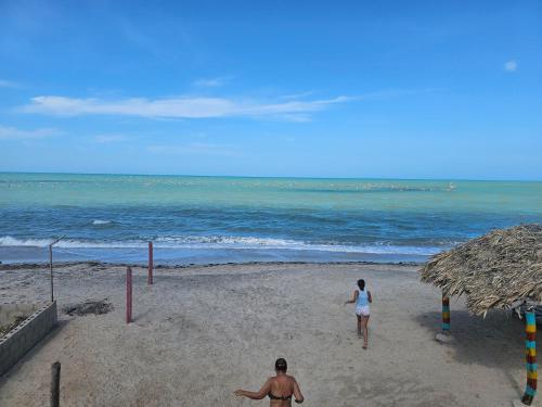 habitación frente al mar في Mayapo: شخصان يسيران على الشاطئ بالقرب من المحيط