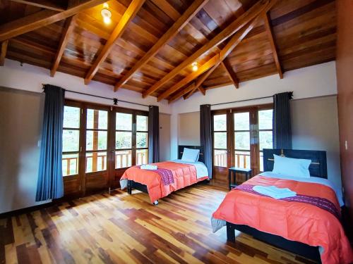 two beds in a room with wooden floors and windows at casa flores in Ollantaytambo