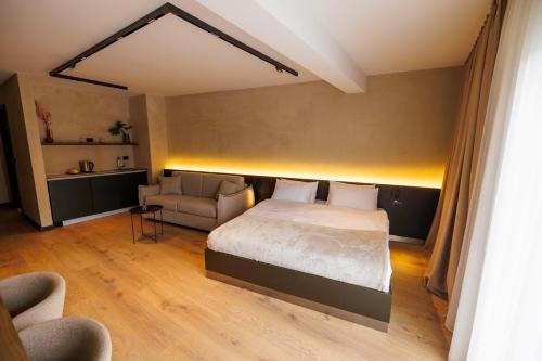 a bedroom with a bed and a couch and a chair at 1863 Boutique Hotel in Peje